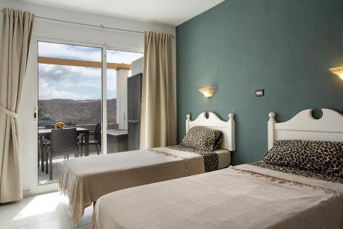 een slaapkamer met 2 bedden en een balkon met een tafel bij Sea View Apartment en Mogán in Playa del Cura