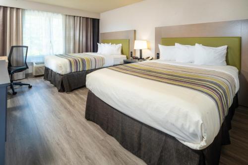 a hotel room with two beds and a desk at Country Inn & Suites by Radisson, Rocky Mount, NC in Rocky Mount