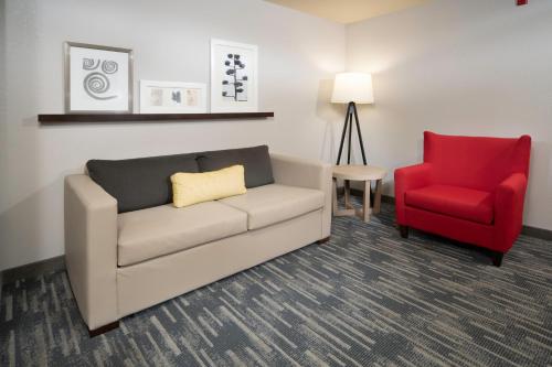 a living room with a couch and a red chair at Country Inn & Suites by Radisson, Rocky Mount, NC in Rocky Mount