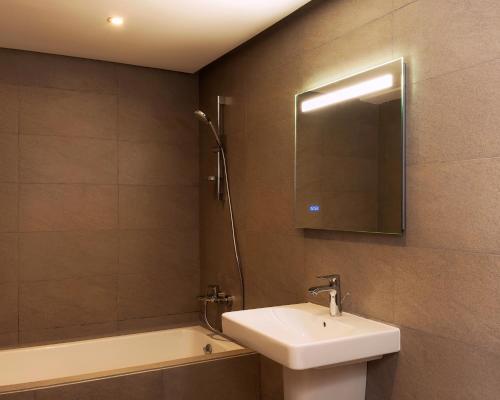 a bathroom with a sink and a mirror and a tub at Radisson Blu Residences Al Hoceima in Al Hoceïma