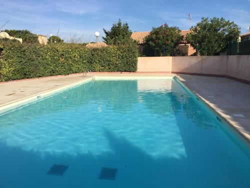 une piscine avec de l'eau bleue dans une cour arrière dans l'établissement Pavillon confort pour 2 personnes GRUISSAN, à Gruissan