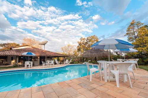 una piscina con tavoli, sedie e ombrelloni di Pousada da Gibinha a Campina do Monte Alegre