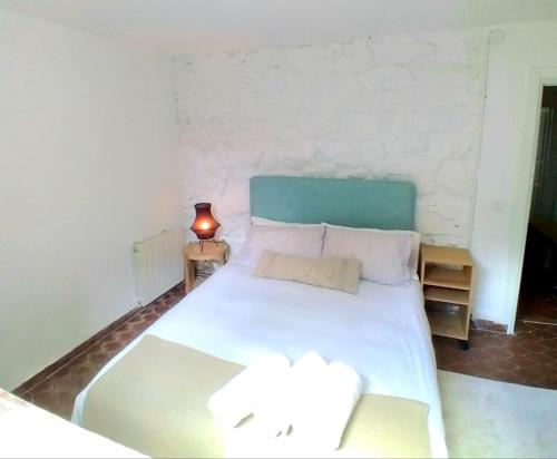 a bedroom with a white bed and a lamp on a table at LA MALINCHE in Segovia