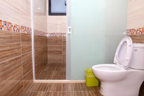 a bathroom with a toilet and a glass shower at Yuan Homestay in Chenggong