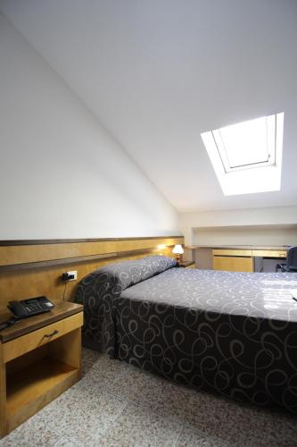 a bedroom with a bed and a skylight at Hotel Croce Di Malta in Novara