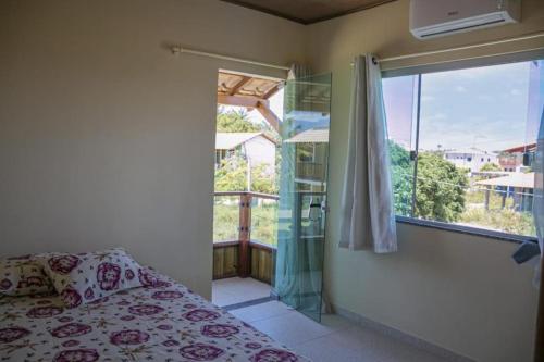 um quarto com uma cama e uma grande janela em Village Taipu de Fora em Maraú