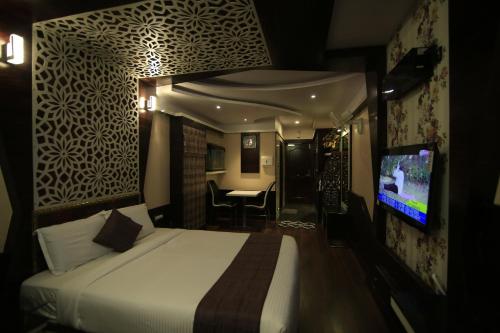 a hotel room with a bed and a flat screen tv at Beverly villa in Ooty