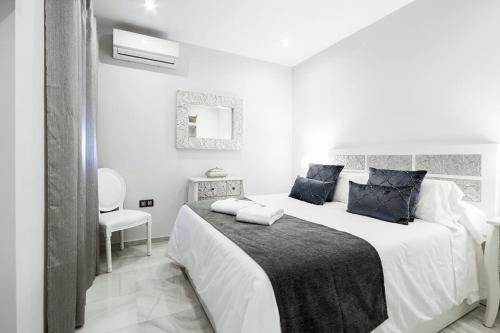 a white bedroom with a large bed with blue pillows at Little LIBERTAD Heart of Cadiz Grupo AC Gestion in Cádiz