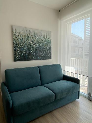a blue couch in a living room with a painting at Aura Marina Casa Vacanze in Polignano a Mare