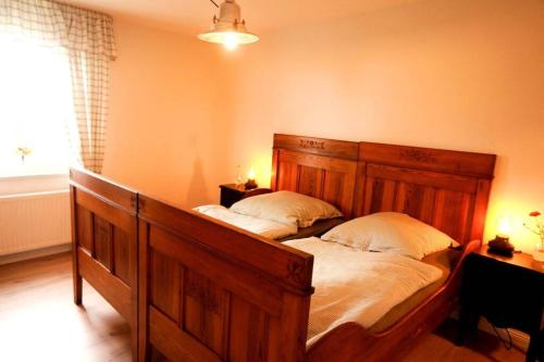 - une chambre avec un grand lit en bois et 2 oreillers dans l'établissement Gutshof Dobschütz - Urlaub auf dem Bauernhof, à Nossen