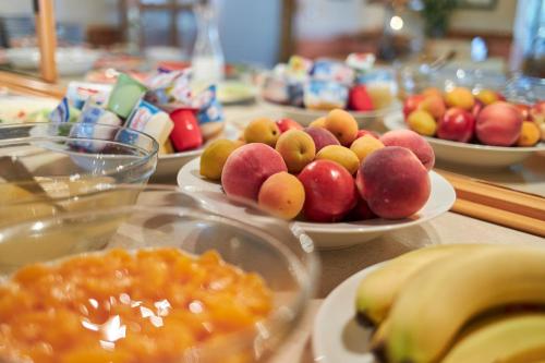 a table topped with bowls of fruit on plates at Flairhotel Hubertus in Bad Zwischenahn