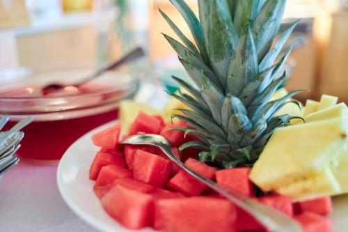 a plate of watermelon and cheese with a pineapple on it at Flairhotel Hubertus in Bad Zwischenahn