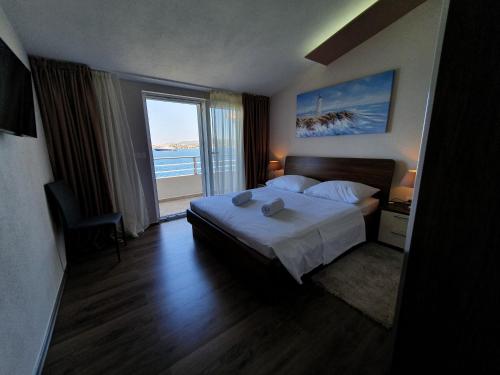 ein Hotelzimmer mit einem Bett und einem großen Fenster in der Unterkunft Beach Apartments Maris in Rogoznica