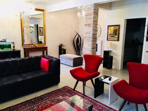 a living room with a black couch and red chairs at Hotel das Palmas in Florianópolis