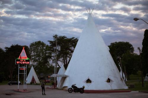 un bâtiment en forme de cône blanc avec un panneau et une moto dans l'établissement Historic Wigwam Village No 2, à Cave City