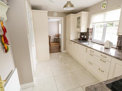 a kitchen with white cabinets and a tile floor at Curragh Hill in Westport