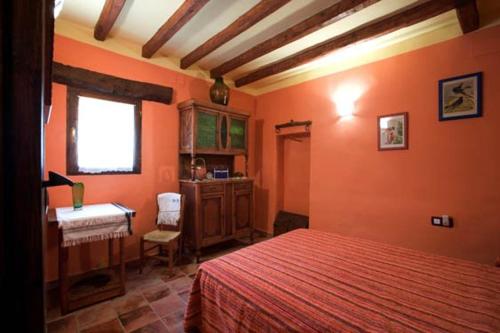 1 dormitorio con paredes de color naranja, 1 cama y escritorio en apartamento Rejola, en Calatayud