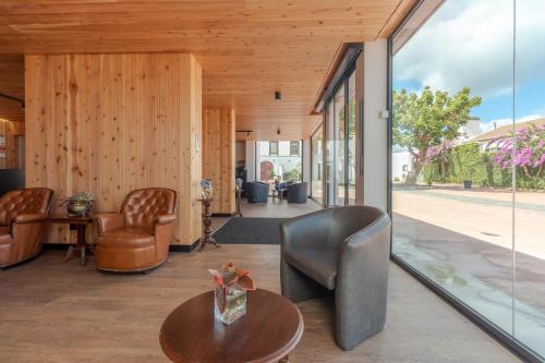 a lobby with chairs and a table and glass walls at Solar Do Conde Garden Hotel in Capelas