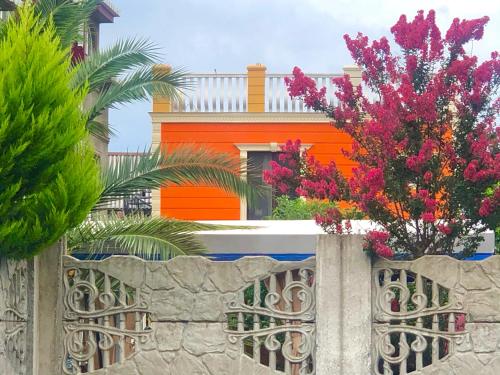 een oranje huis achter een stenen hek met bloemen bij ORANGE INN in Chakvi
