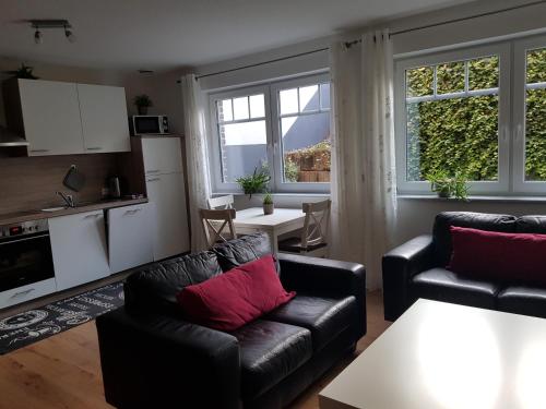 a living room with two leather couches and a kitchen at Ferienwohnungen Liliencron - Fewo I in Enger