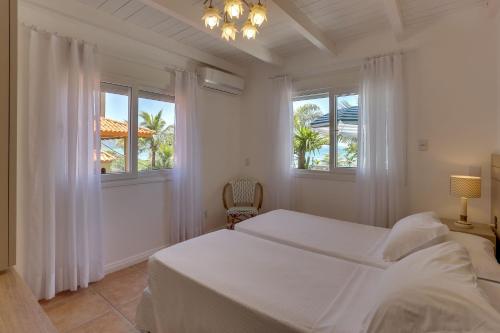 1 dormitorio blanco con 1 cama y 2 ventanas en Villas Jurerê Residences, en Florianópolis