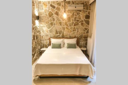 a bed in a room with a stone wall at Your cozy downtown home - Studio in Larisa