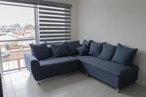 a blue couch in a room with a large window at Departamento La Choza Central Pool in GDL downtown in Guadalajara