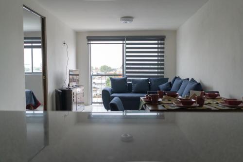 a living room with a blue couch and a table at Departamento La Choza Central Pool in GDL downtown in Guadalajara