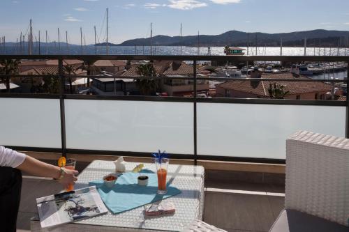 a table on a balcony with a view of a harbor at Hôtel Baptistin in Le Lavandou