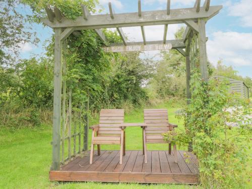 two wooden benches sitting under a gazebo at Lakeside Cottage in Boyle