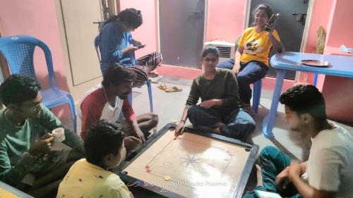 a group of people sitting in a room playing a game at Abhi Homestay Hampi in Hampi