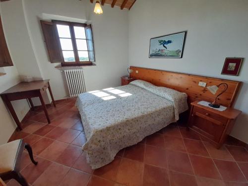 a bedroom with a bed and a table and a window at Borgo Beccanella in Asciano