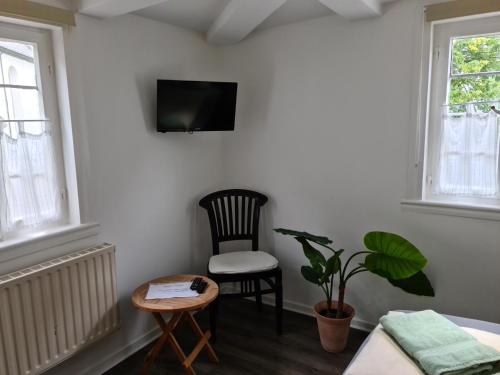 a room with a chair and a tv on a wall at Pilgrims Gästeapartements in Meschede