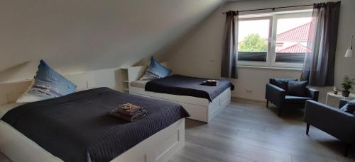 a bedroom with two beds and a chair and a window at Am Anker in Langballig