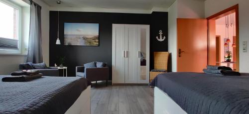 a bedroom with two beds and a chair and a door at Am Anker in Langballig