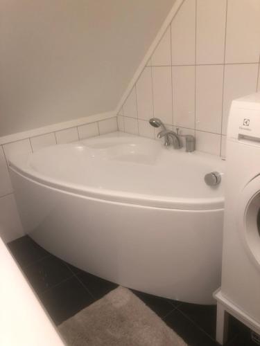 La salle de bains est pourvue d'une baignoire blanche et de toilettes. dans l'établissement Aid og Svein’ s sentrumsnære panorama hjem, à Kristiansand