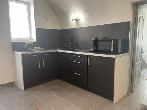 a kitchen with black cabinets and a microwave at Roman in Alès