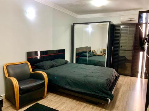 a bedroom with a bed and a chair and a mirror at Flat em São Vicente com piscina na cobertura in Rio Grande da Serra