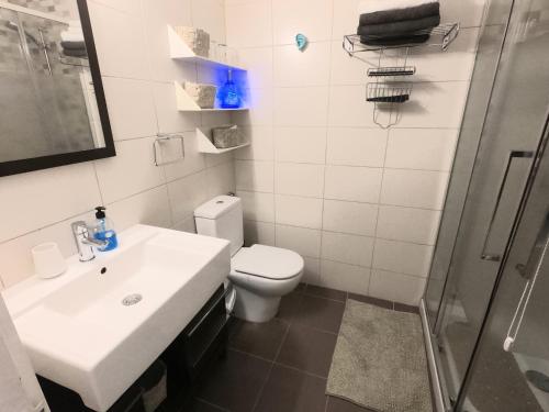 een badkamer met een toilet, een wastafel en een douche bij Charming Sunset View Apt Heater Pool Costa Adeje in Adeje