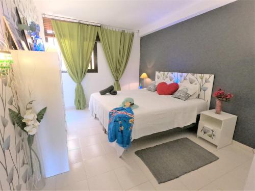 een slaapkamer met een wit bed en groene gordijnen bij Charming Sunset View Apt Heater Pool Costa Adeje in Adeje