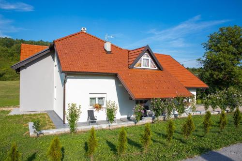a small white house with an orange roof at Apartmani Leptir in Rakovica