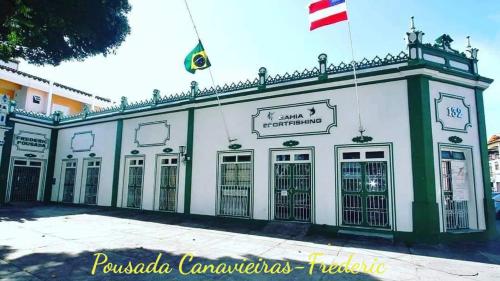 Pousada Canavieiras Frederic في كانافييراس: مبنى اخضر وابيض عليه علم
