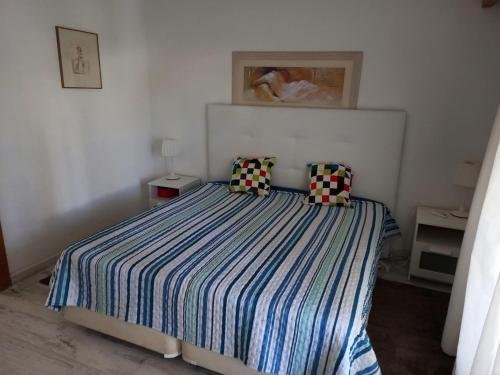 a bedroom with a bed with a striped comforter and pillows at Quinta do Lago - Beach,Ténis, Bikes in Quinta do Lago