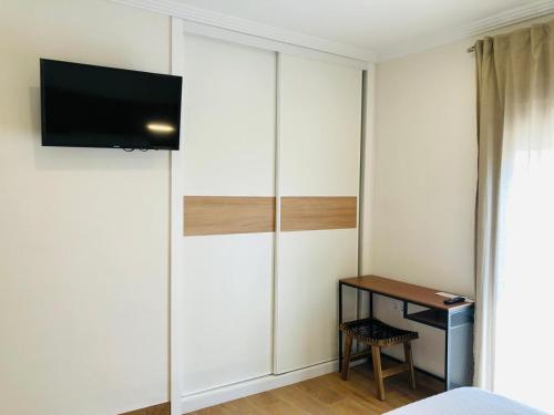 1 dormitorio con armario, escritorio y TV en El Montoro, en Cádiar