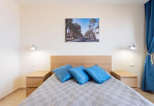a bedroom with a bed with blue pillows at Sunny Castillo Apartment in Costa de Antigua