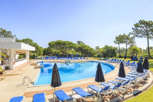 a swimming pool with chairs and umbrellas at Quinta do Lago - Beach,Ténis, Bikes in Quinta do Lago