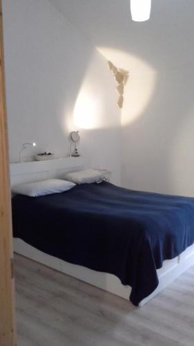 uma cama num quarto branco com um cobertor azul em Vetralla Terme Viterbo em Vetralla