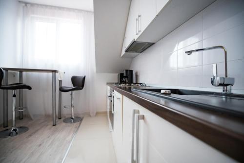 a kitchen with a sink and two bar stools at Apartament Vlad in Turda
