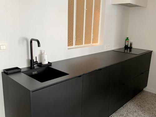 a kitchen with a sink and a black counter at Theodore Oostende-zorgeloos genieten in stijl op de perfecte locatie in Ostend