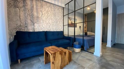 een blauwe bank en een houten tafel in een kamer bij Apartament MAGMA z basenem Morska Klifowa Rewal in Rewal